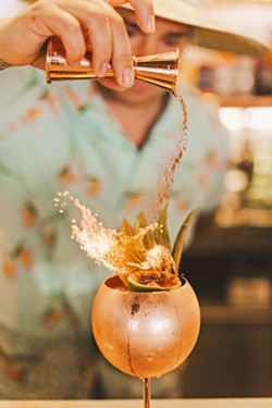 PICK YOUR POISON The Alchemists' Garden co-owner and bartender Tony Bennett sprinkles cinnamon into the flames of the Belladonna, butter-washed Krobar navel rum, pineapple and orange juice, falernum, and creme of coconut. - COURTESY PHOTOS BY SARAH KATHLEEN PHOTOGRAPHY