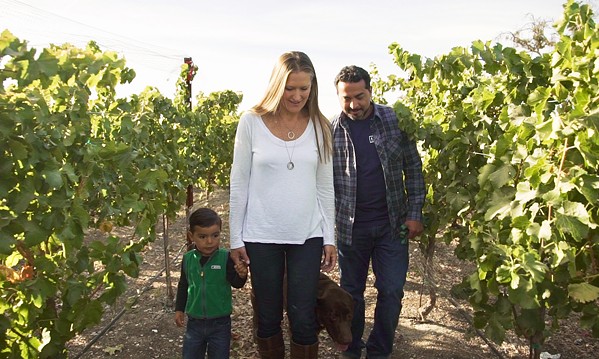 LA FAMILIA Winemaker Edgar Torres; his wife, Erika; 8-year-old son, Evan; and chocolate Labrador, Osos, enjoy Paper Street Vineyard in Paso Robles. Torres sources grapes from the vineyard, owned by J. Dusi Wines. - PHOTO COURTESY OF BODEGA DE EDGAR