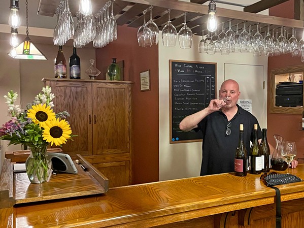 THE PERFECT POUR Store manager Tom Nicholas samples wares at CCW's intimate, 15-seat tasting room. Patrons can order a flight, glass, or bottle of wine, as well as draft or bottled beer. - PHOTO BY CHERISH WHYTE