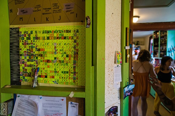 SAME AS IT EVER WAS At left, the chore wheel and chore chart keep housemates organized. The chore wheel has been a staple since 1980, with few changes in that time. At right, housemates cook, clean, and talk in the kitchen, a timeless scene at The Establishment. - PHOTO BY JAYSON MELLOM