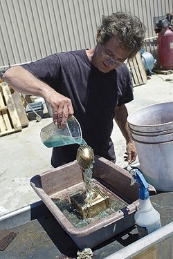 Baxter pours a secret chemical mix over the sculpture to create the patina. - PHOTO BY STEVE E. MILLER