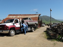 OFF THE FARM :  Tow company workers endeavor to haul away one of 26 vehicles county code officials had a warrant to remove from Dan DeVaul&rsquo;s Sunny Acres ranch. In the end, only six were removed. - PHOTO BY PATRICK HOWE