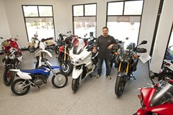 SHINY TWO WHEELED MACHINES:  Surrounded by just some of SLO Motorsports stock of Yamahas, Moto Guzzis, Aprilias, Vespas and Piaggio, manager Lance Tanneris is ready to help you buy your next motorcycle. - PHOTO BY STEVE E. MILLER