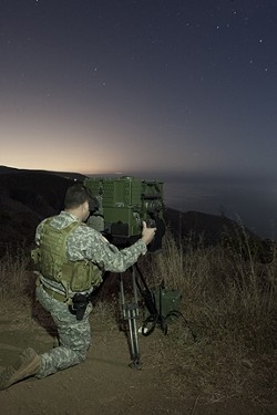 EYES ON THE WATER :  A National Guard soldier peers through a LRAS-3 long-range night vision scope to scan the horizon for suspicious watercraft. The U.S. National Guard&rsquo;s counter-drug coastal surveillance team took New Times for a ride-along atop the hills overlooking the Ventura County coastline. - PHOTOS BY STEVE E. MILLER