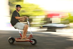 ELECTRIC PERSONALITY :  San Luis Rides owner, Jake Carter, buzzes past traffic on an electric Go-Ped Scooter. - PHOTO BY STEVE E MILLER