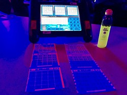 BRIGHT FUTURE :  An automated bingo machine, a bingo dauber, and cards glow under black lights at the Chumash Casino. - PHOTO BY TREVER DIAS