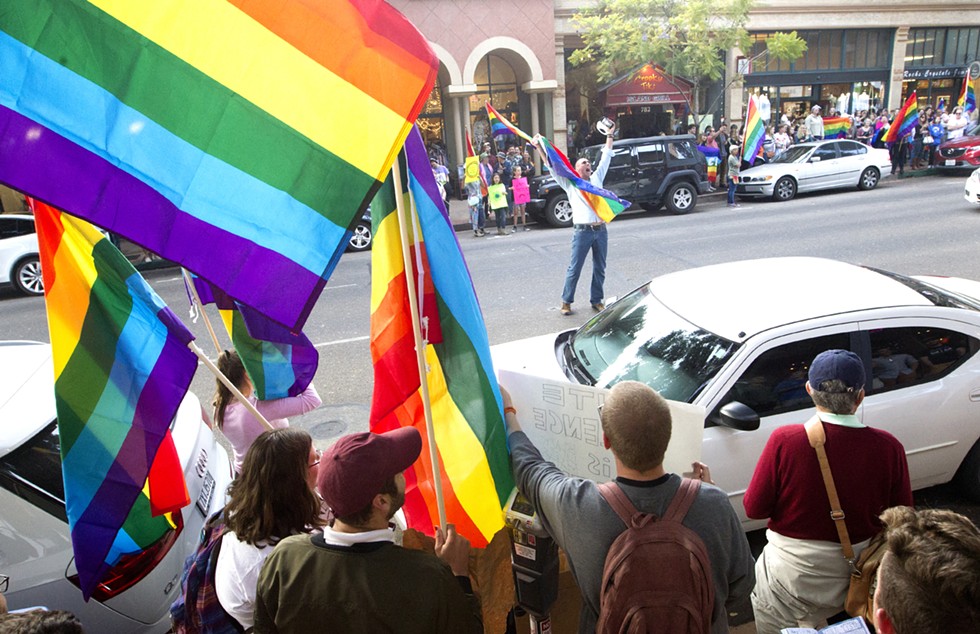 IN THE STREETS A demonstrator lifts up a Pride flag and yells on Higuera Street in SLO during the “Show Your True Colors” rally in support of the LGBTQ community on June 7. - PHOTO BY JASON MELLOM