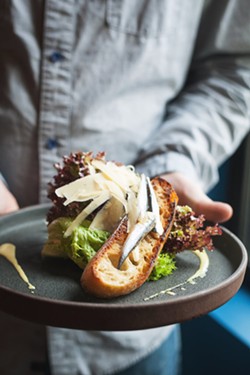 TAP THIS APP Butter lettuce grown at the restaurant's local farm is topped with white anchovies, house Cesar dressing, shaved parmesan, and grilled sourdough. - PHOTO BY HAYLEY THOMAS CAIN