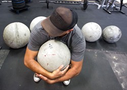 ATLAS Dave LaCaro prepares to lift a 95-pound atlas stone during a SLO Strong workout. - PHOTO BY JAYSON MELLOM