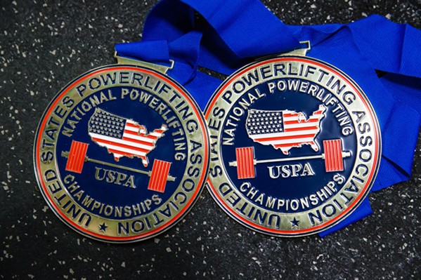LOST AND FOUND After her powerlifting medals were destroyed in a house fire in July, Juarez had some of them remade by the U.S. Powerlifting Association, including these two for first place and best lifter at a competition. - PHOTO BY JAYSON MELLOM