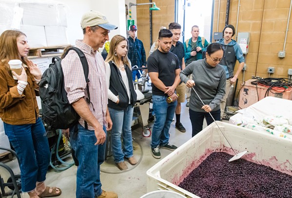 INTRO TO WINEMAKING Alfredo Koch (second from left), instructor and coordinator of the Allan Hancock College viticulture/enology program, leads his class in checking levels of fermentation on grapes in the student winery. - PHOTO BY JAYSON MELLOM