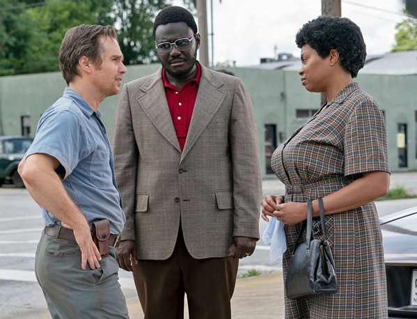 GETTING TO KNOW YOU Klan leader C.P. Ellis (Sam Rockwell, left) and civil rights activist Ann Atwater (Taraji P. Henson, right) learn to respect one another when they participate in a community meeting about school integration led by Bill Riddick (Babou Ceesay, center), in The Best of Enemies. - PHOTO COURTESY OF ASTUTE FILMS