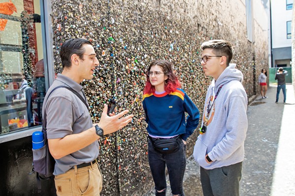 GUM HISTORY Austin Bertucci (left) explains the origins of Bubblegum Alley to two visitors from Phoenix, Arizona. Part of his job as the Downtown SLO ambassador is to engage with tourists about the city. - PHOTOS BY JAYSON MELLOM