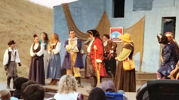 TREACHERY Long John Silver (center, in the iconic red coat) convinces Young Jim Hawkins (far left) to trust him, gaining passage to Treasure Island aboard the Hispaniola. - PHOTOS BY ANDREA ROOKS