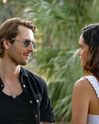 FATAL ATTRACTION An undercover mole (Glen Powell, left) pretending to be a hit man gets dangerously close to a client (Adria Arjona, right) who hires him to kill her husband, in Netflix's Hit Man.
