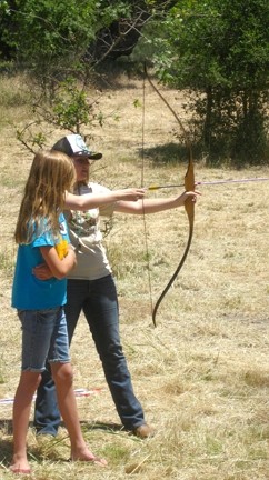 TAKE AIM :  A Camp Natoma regular helped a younger girl take her first shot with a bow and arrow. The camp provides weeklong, overnight retreats that include swimming, crafts, and archery for kids ages 6 to 17. - PHOTO BY NICK POWELL